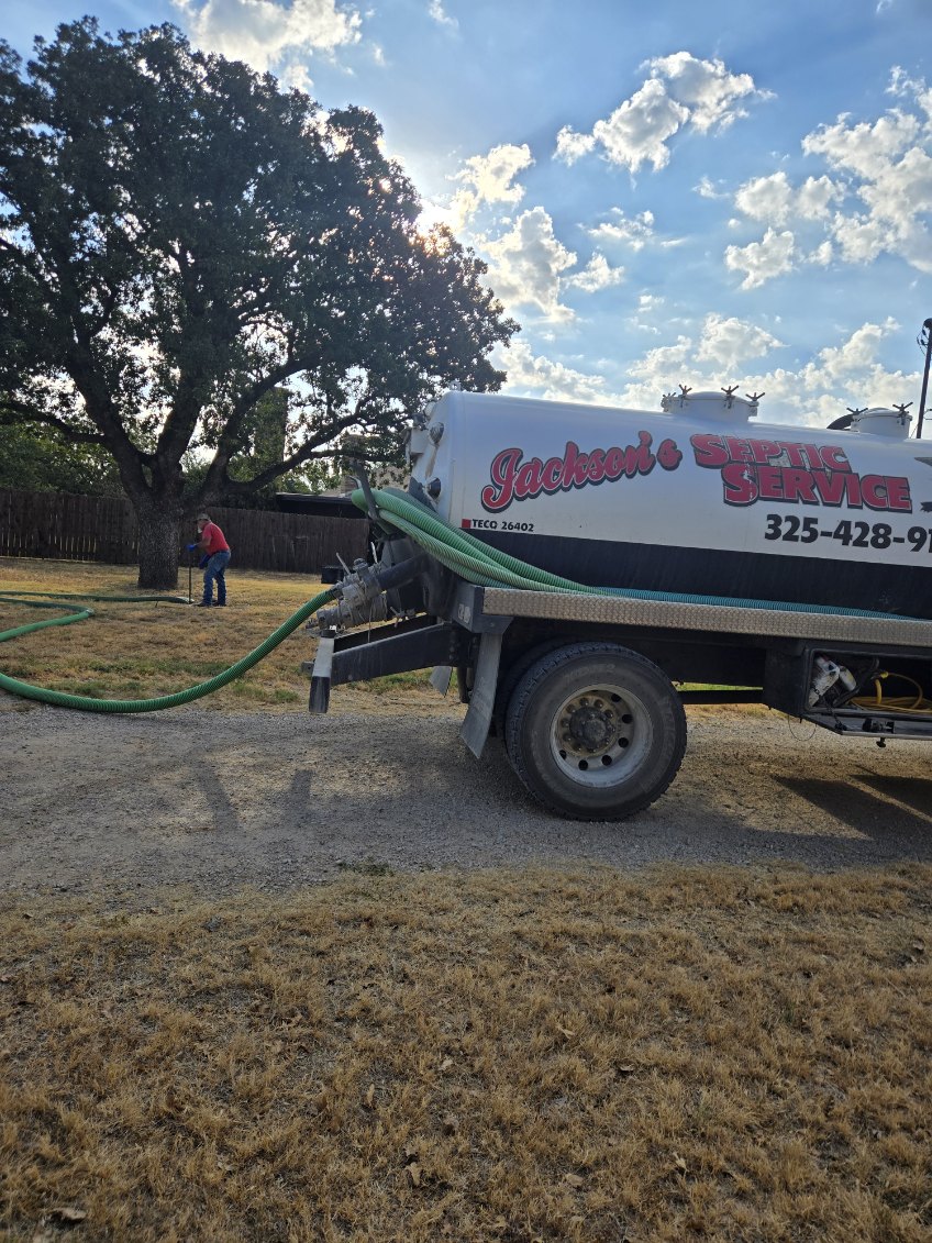Jackson's septic truck with hose run across a residential yard