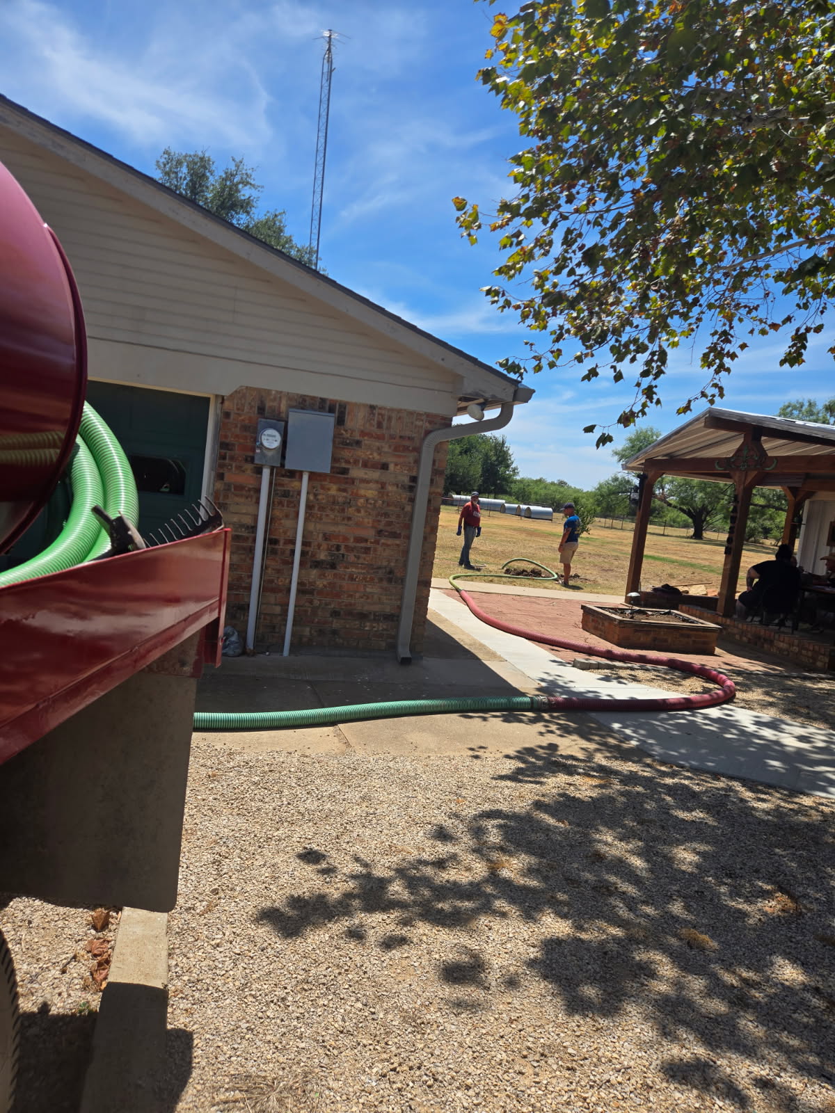 Service hose routed around a brick home during septic work