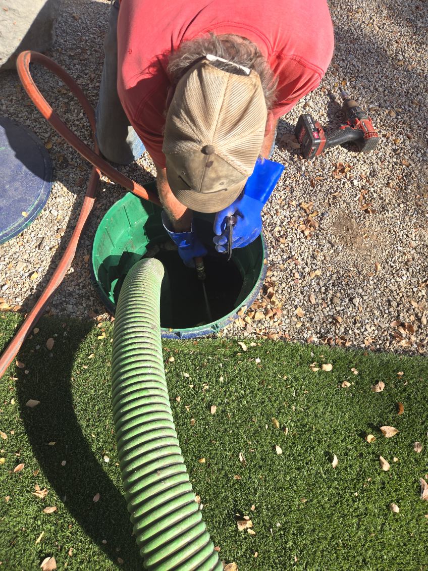 Close-up of a technician working inside an open septic tank access