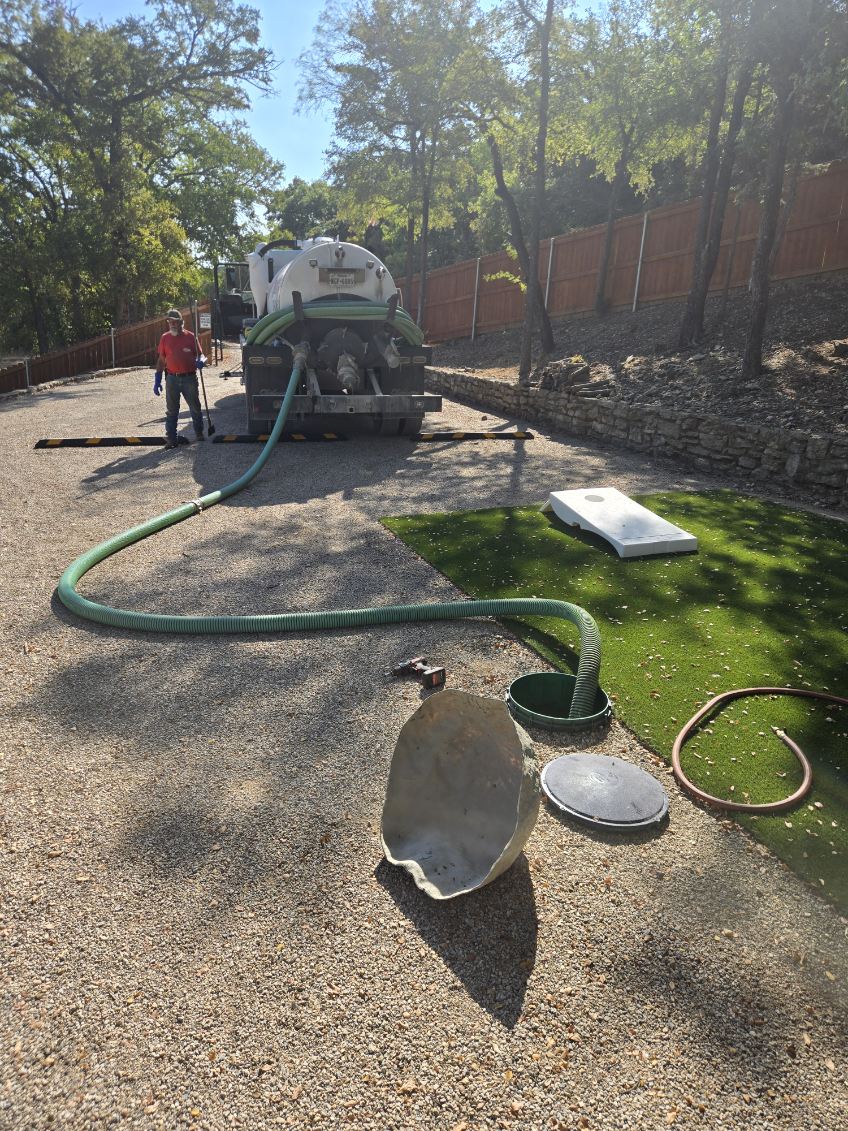 Vacuum hose from the truck connected to a residential septic tank opening