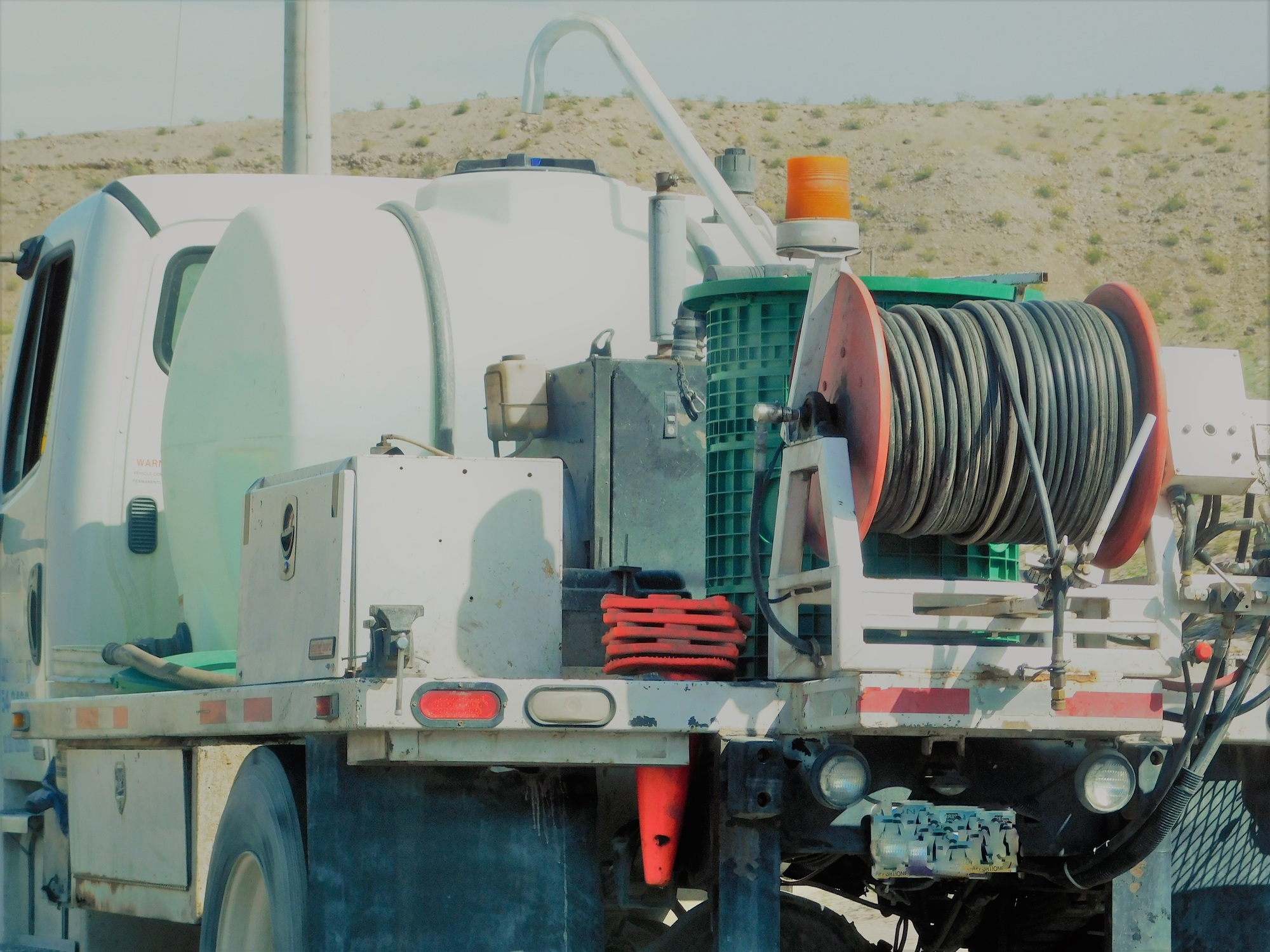 Service truck equipped with hose reel and tank for septic and drain work